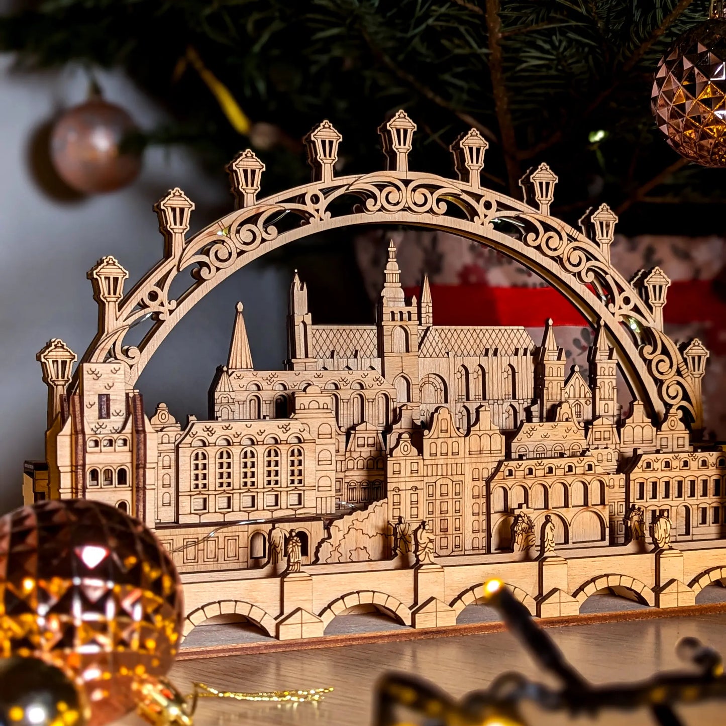 Tight straight front view focusing on a miniature historic castle cathedral and stone bridge made from laser cut plywood.