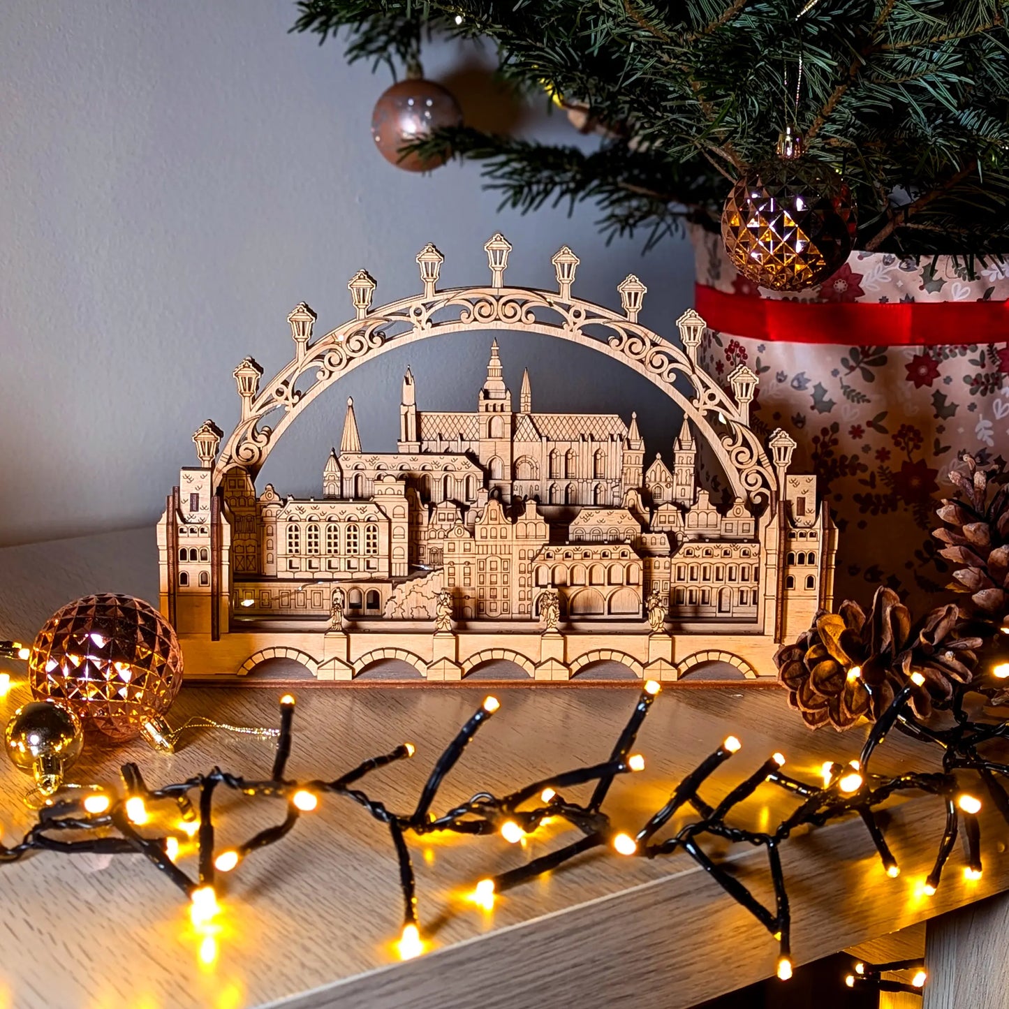 Front view of a glowing Prague cityscape arch display styled with warm fairy lights, beautifully made of laser cut plywood.