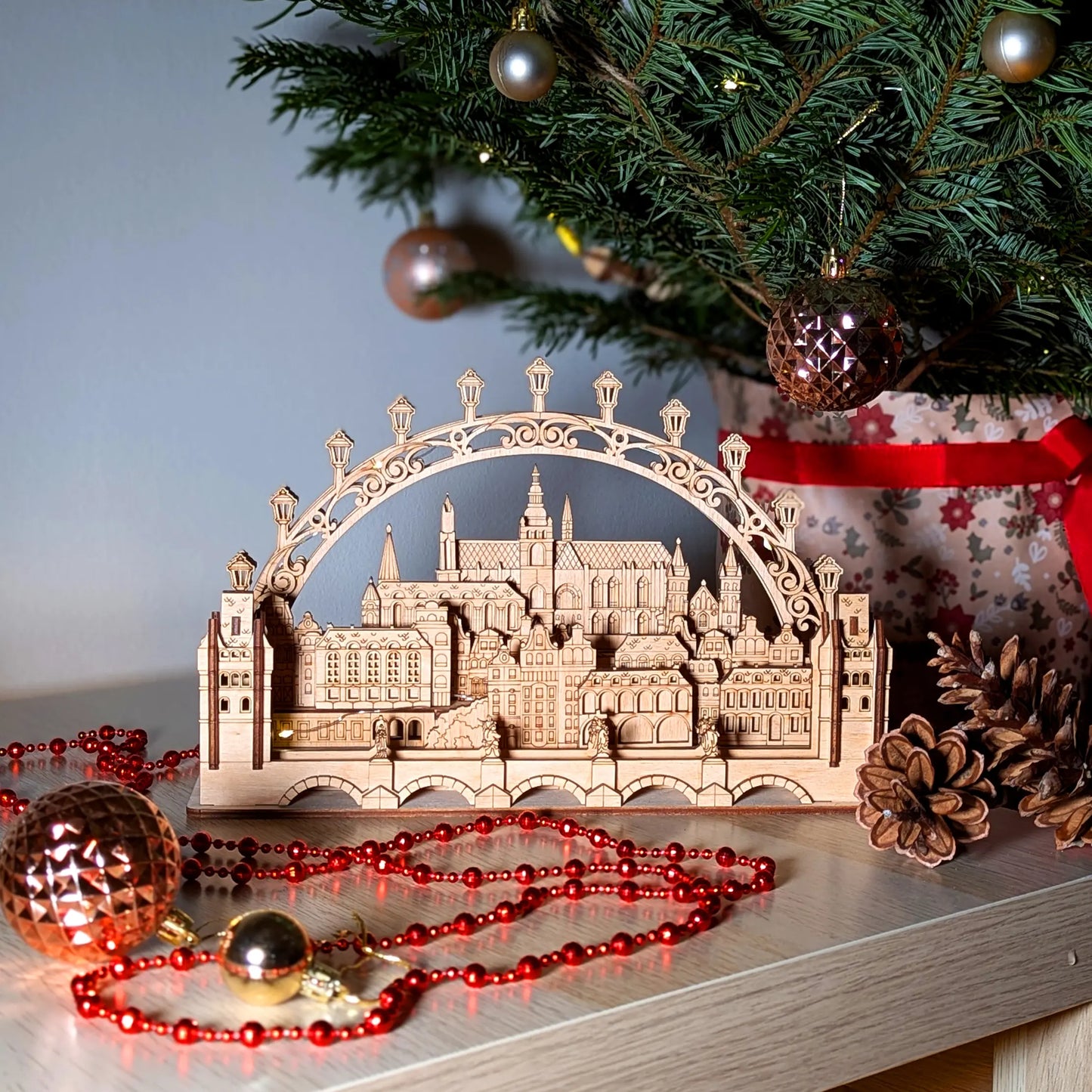 A straight front view of a miniature Prague city light arch centerpiece staged with holiday decor and laser cut plywood.