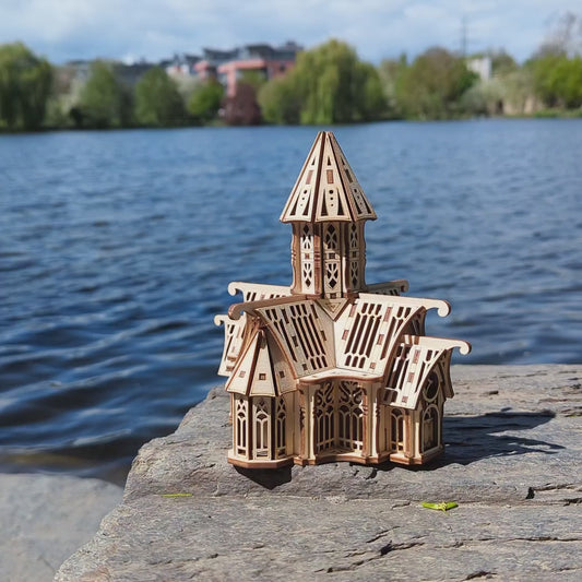 Laser cut plywood fantasy castle miniature catching bright sunlight on a rock surface