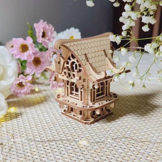 Detailed miniature fairy house of laser cut plywood, elegantly displayed among spring flowers and soft lighting.