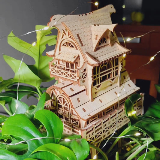 laser cut plywood miniature wizard house decorated with small glowing lights inside a green plant.