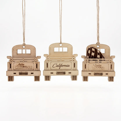 Set of three laser cut plywood pickup truck ornaments hanging on jute twine, isolated on white background.
