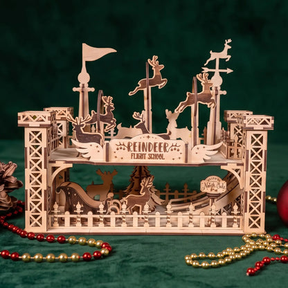 A wooden laser-cut Christmas Diorama of REINDEER FLIGHT SCHOOL on a green velvet background with red and gold bead garlands.