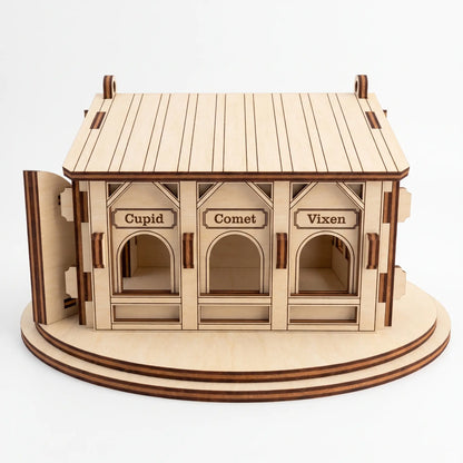Side view of laser cut plywood reindeer barn showing feeding stalls engraved with Cupid, Comet, and Vixen names
