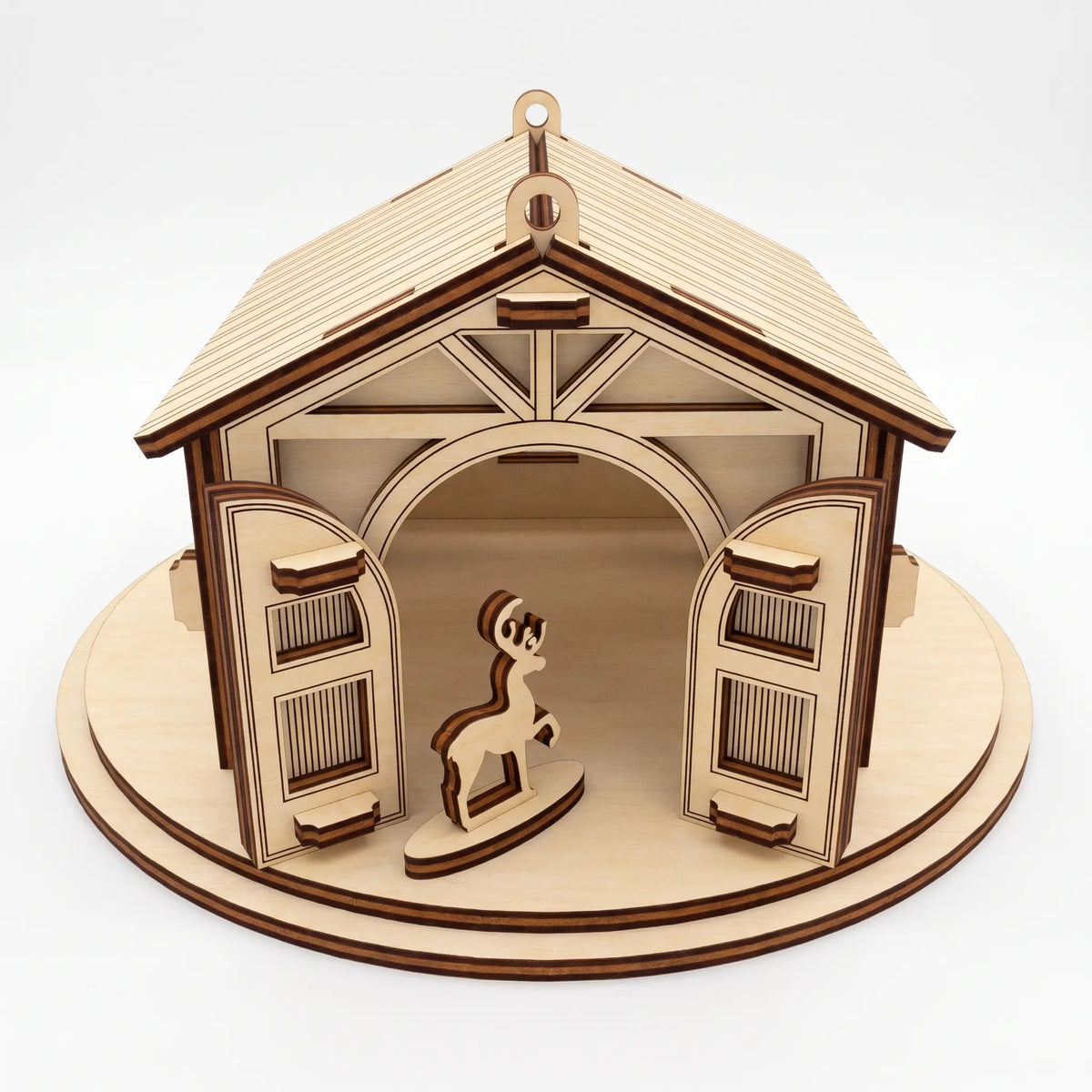 Front view of laser cut plywood reindeer stable with open arched double doors and small standing deer on round base