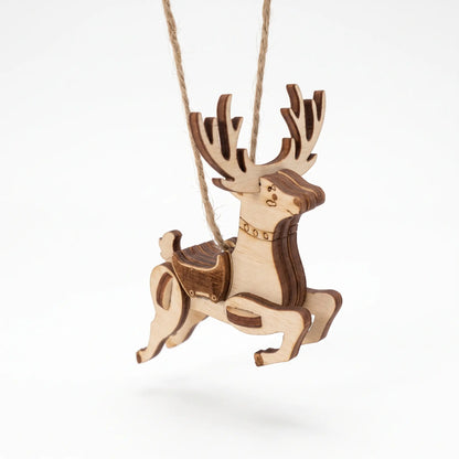 Perspective view of a laser cut plywood flying reindeer ornament with carved saddle hanging against a clean white backdrop.