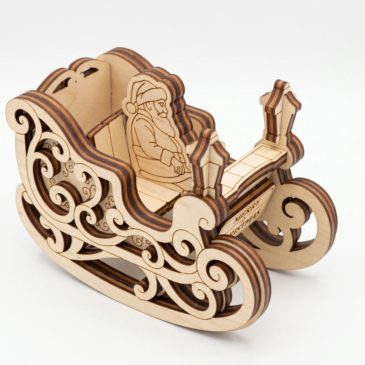 High angle view of laser cut plywood Santa sleigh model with ornate swirl runners isolated on plain white.