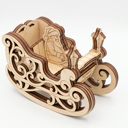 High angle view of laser cut plywood Santa sleigh model with ornate swirl runners isolated on plain white.