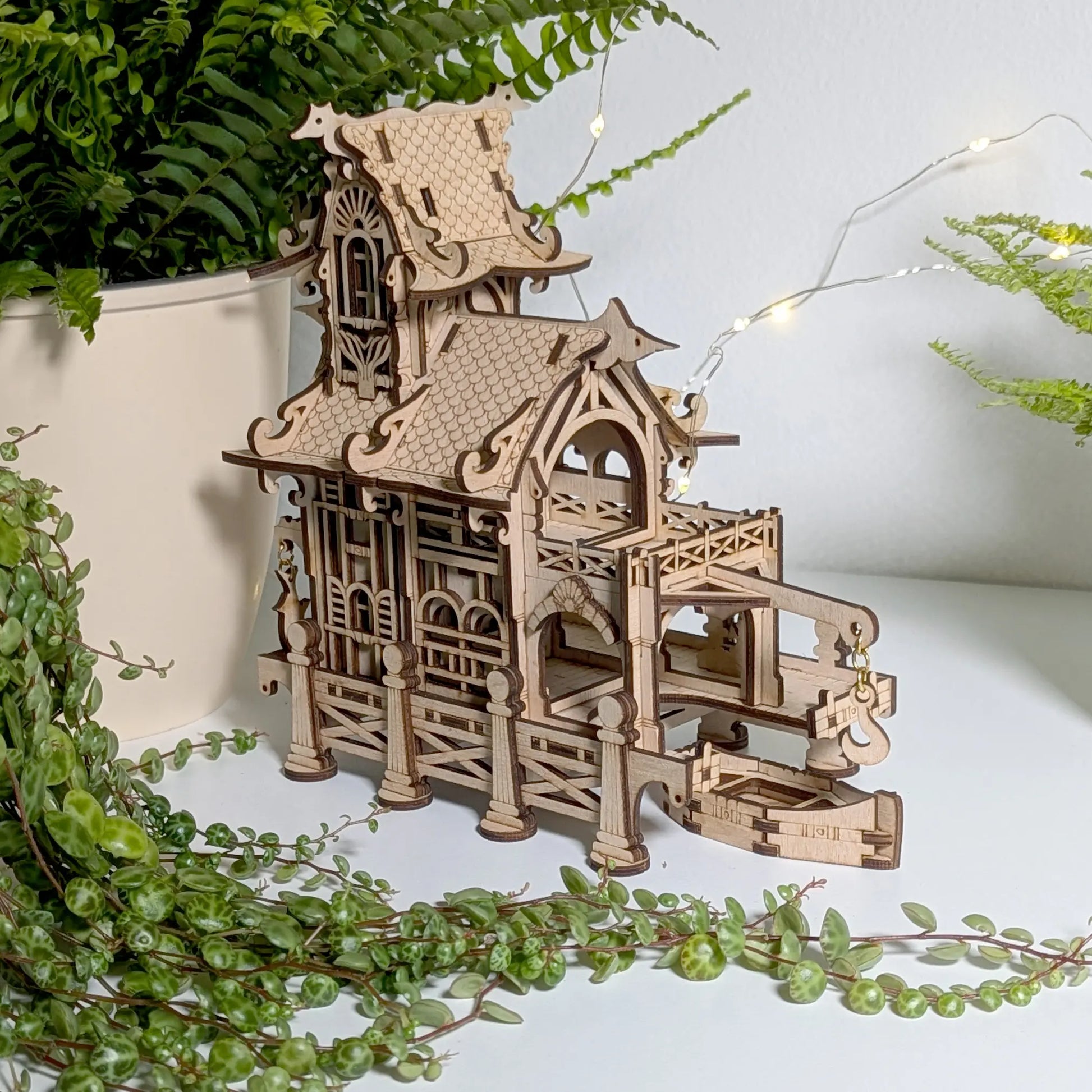 Cozy side perspective shot of a decorative 3D mini lighthouse base and fence built from detailed laser cut plywood.