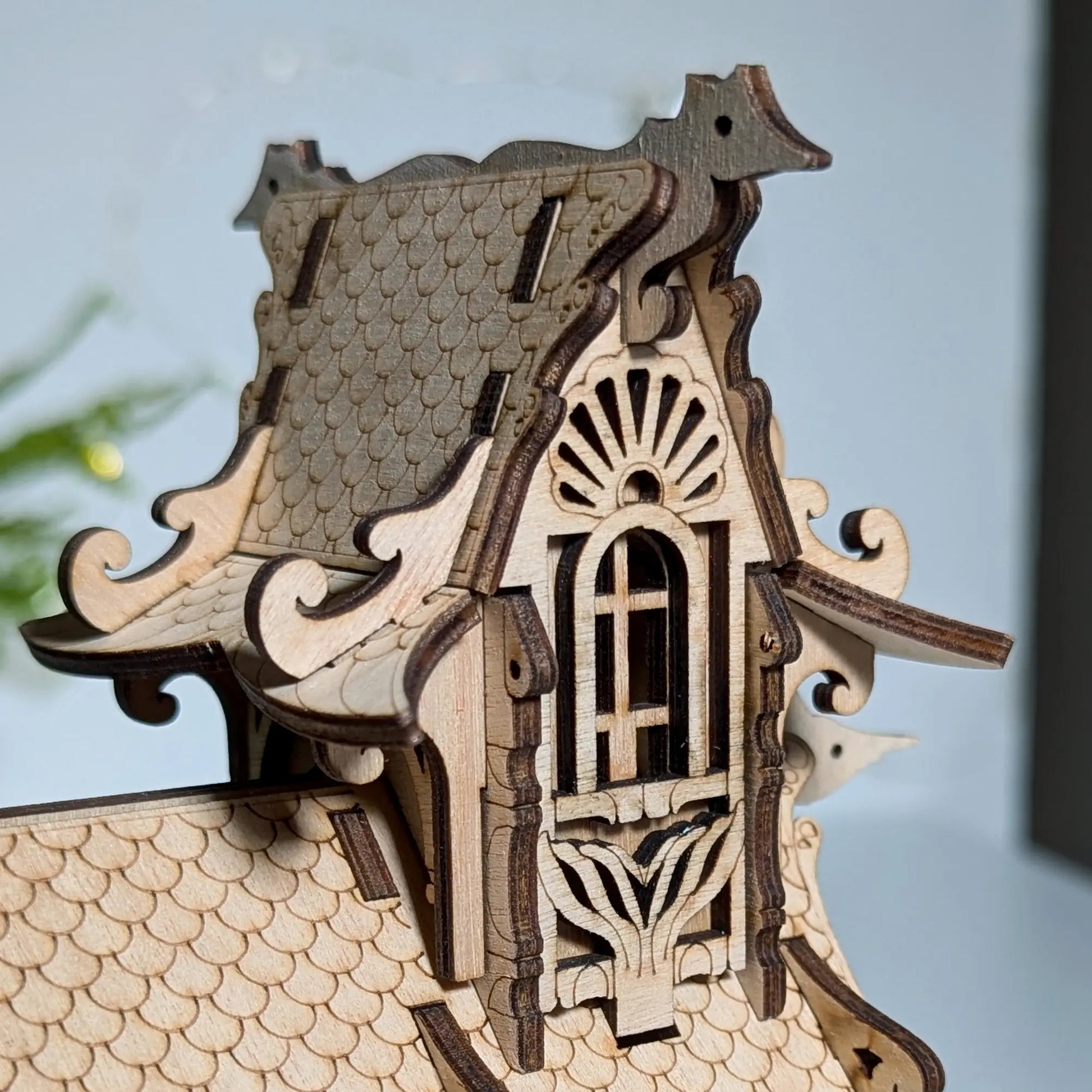 Macro close-up focusing on a tiny engraved seagull on the decorative roof ridge line of a laser cut plywood house.