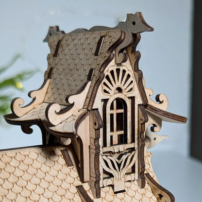 Macro close-up focusing on a tiny engraved seagull on the decorative roof ridge line of a laser cut plywood house.