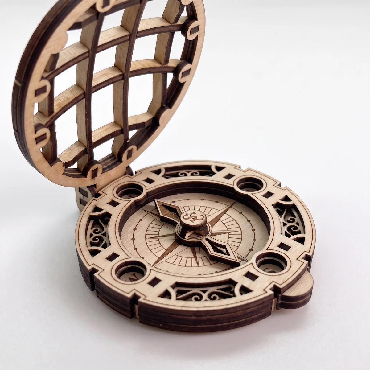 Close-up side view of laser cut plywood Santa compass showing open lattice lid and layered dial details on white
