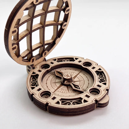 Close-up side view of laser cut plywood Santa compass showing open lattice lid and layered dial details on white