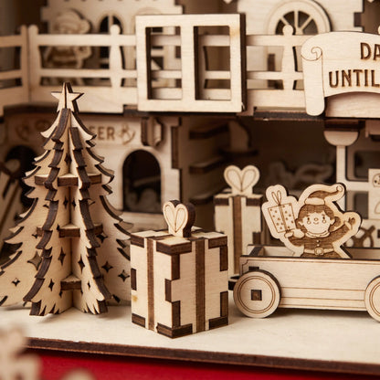 Close-up of laser cut plywood Santa workshop showing elf in wooden cart, slotted gift boxes, and pine tree