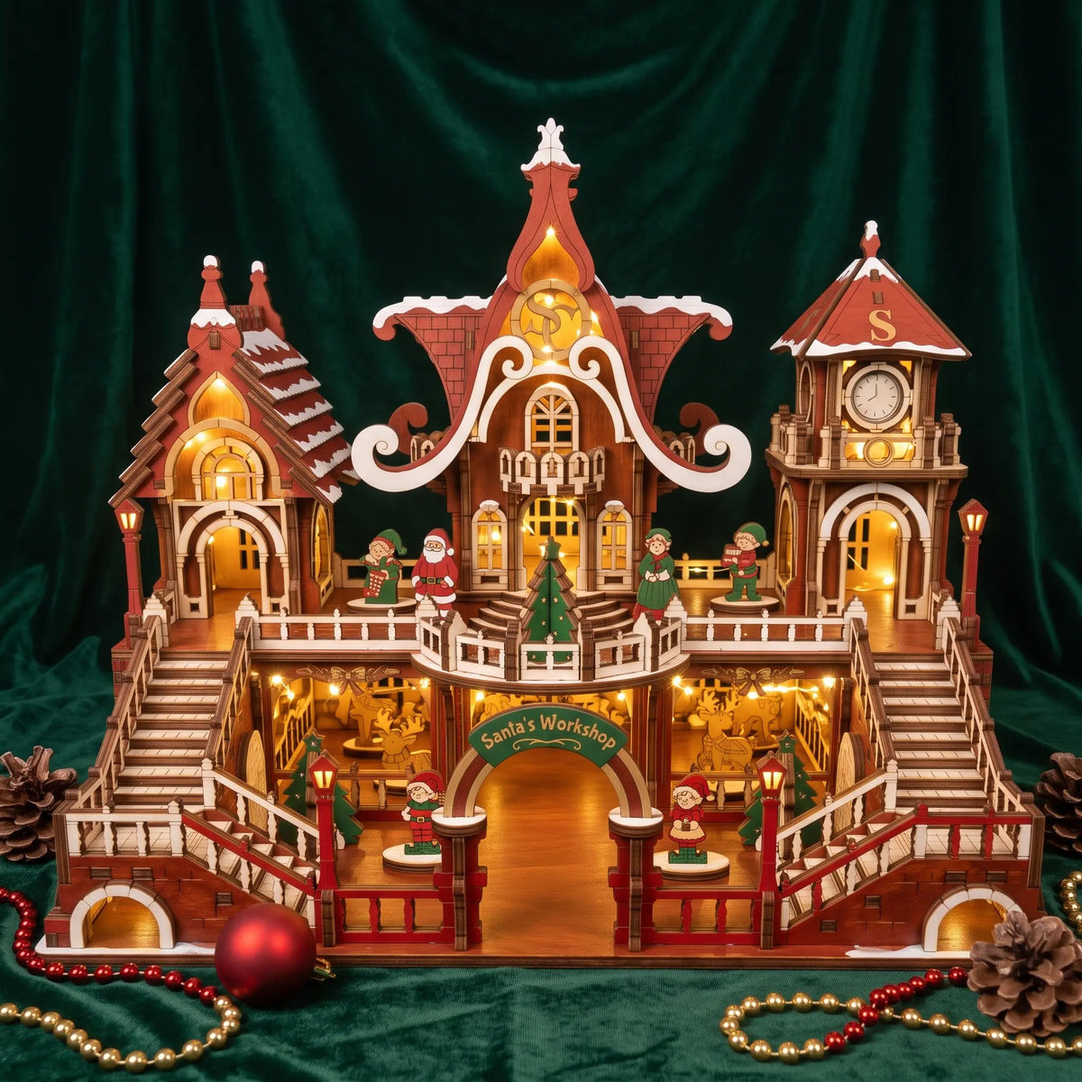 Illuminated painted laser cut plywood Santa workshop castle on emerald green velvet with warm lights.