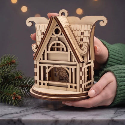 Hands hold laser cut plywood fairy tale Santa workshop house showing Santa seated inside, with holiday background