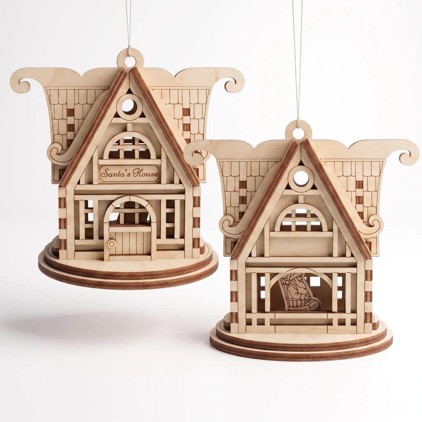 Front and rear views of hanging laser cut plywood Santa’s House ornaments on round pedestals against plain white