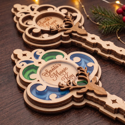 Close-up of colored acrylic and laser cut plywood Santa magic key ornaments on dark wooden table with holiday fairy lights.
