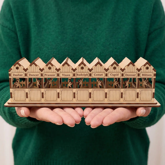 Person in a green sweater holding a miniature laser cut plywood reindeer stable to show actual size.
