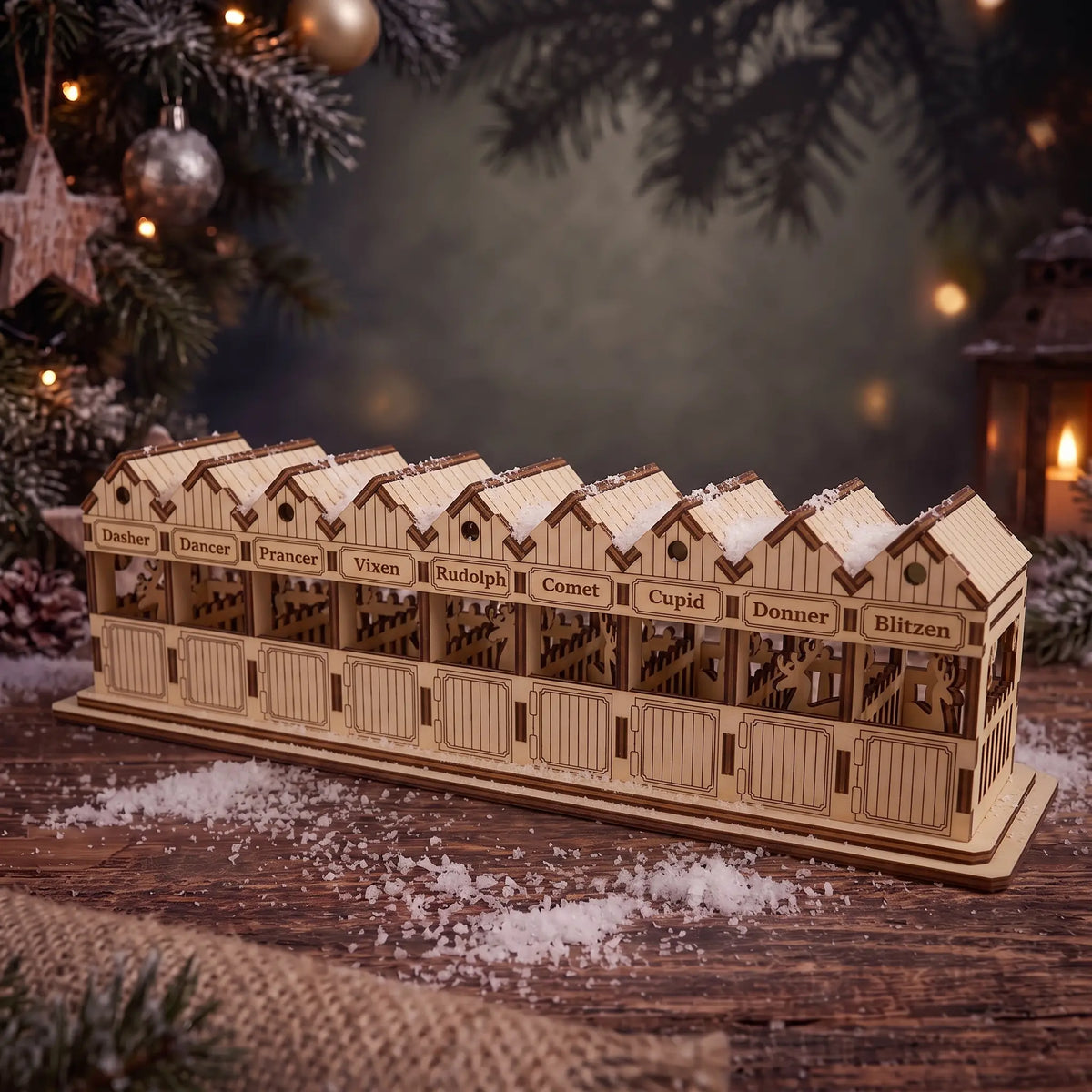 Cozy holiday setting with a laser cut plywood reindeer barn near a Christmas tree and glowing lantern.