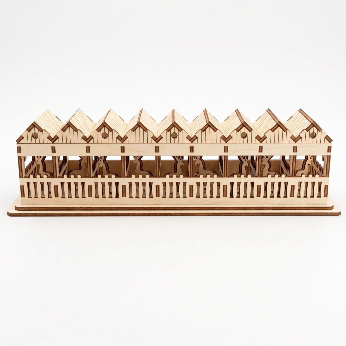 Back view of laser cut plywood reindeer barn on white background, showing slotted fences and stalls.