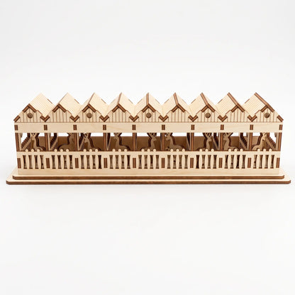 Back view of laser cut plywood reindeer barn on white background, showing slotted fences and stalls.