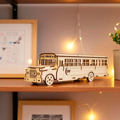 Laser cut wooden plywood school bus model 3D puzzle on a shelf with warm fairy lights. Detailed plywood construction showing "SCHOOL BUS" sign, windows, and wheels. Natural wood grain texture with precise dark burnt edges from laser cutting.
