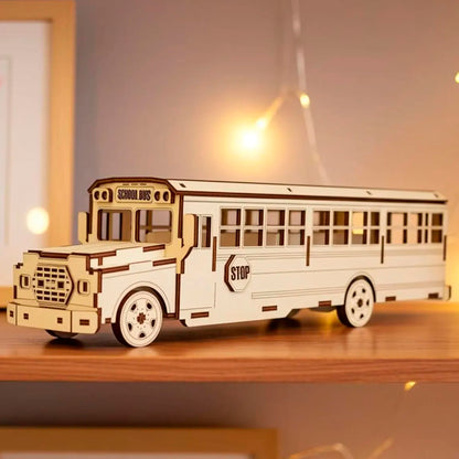Laser cut wooden plywood school bus model 3D puzzle on a shelf with warm fairy lights. Detailed plywood construction showing "SCHOOL BUS" sign, windows, and wheels. Natural wood grain texture with precise dark burnt edges from laser cutting.