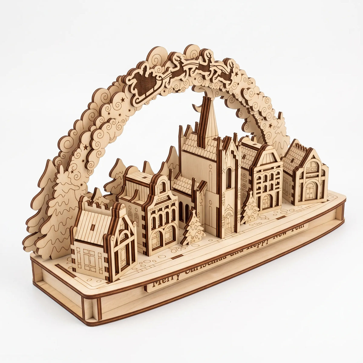 High-angle view of 3D laser cut plywood Christmas village arch with church, miniature houses, and Santa on white background.