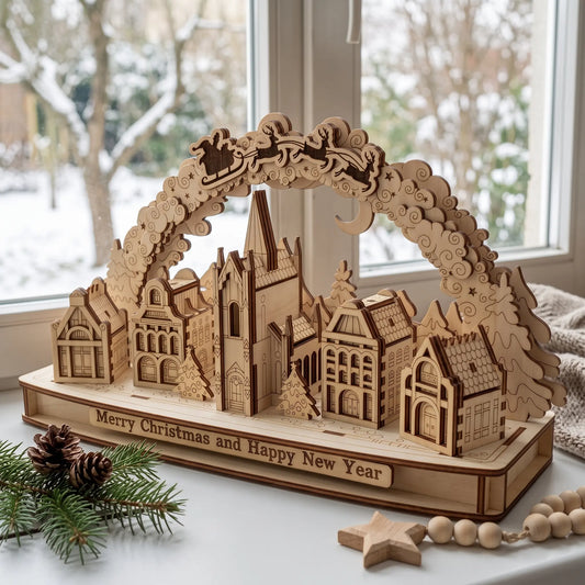 Laser cut plywood holiday village arch placed on windowsill beside pine branch and wooden star against snowy winter view.