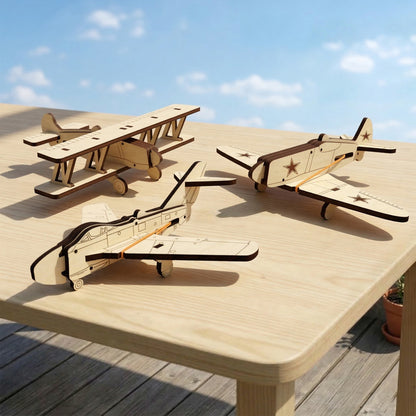 Three diverse aircraft models crafted from laser cut plywood: a biplane and two fighter planes with etched stars. The natural wood miniatures are arranged on a light tabletop outdoors under a sunny sky, highlighting precise assembly and dark edges.