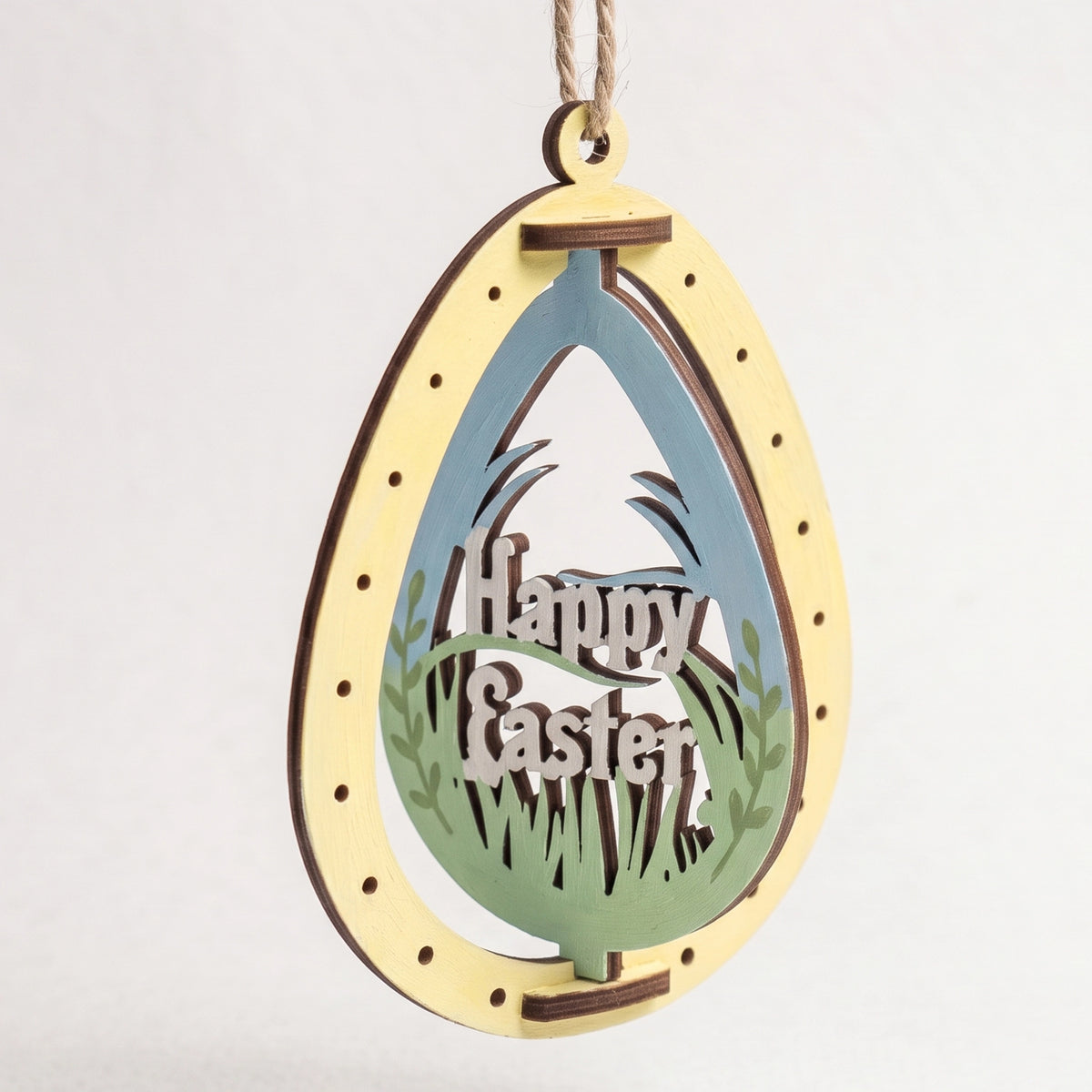 Painted laser cut plywood Easter egg ornament featuring rotating Happy Easter lettering cutout on plain white background.