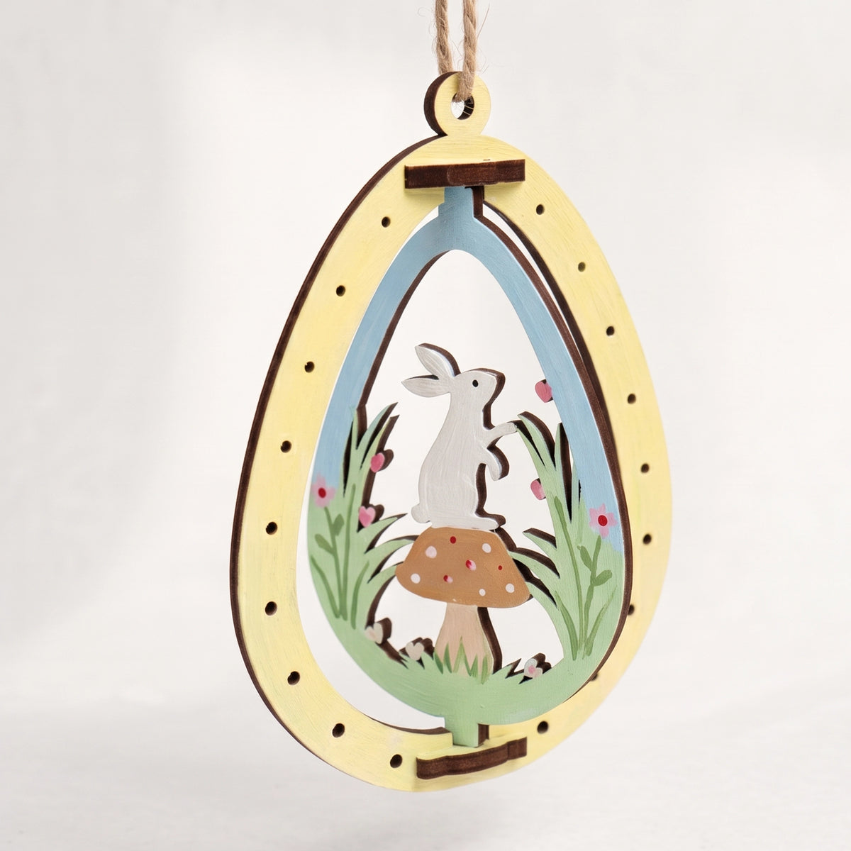 Painted laser cut plywood Easter egg ornament featuring rotating cute bunny standing on a mushroom on plain white background.