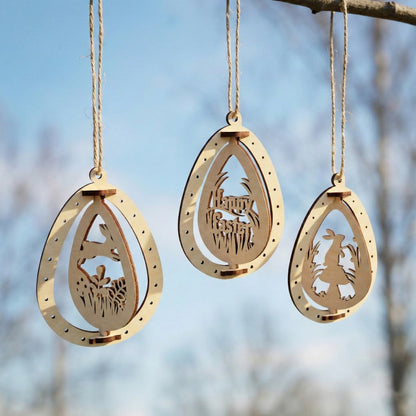 Three laser cut plywood Easter egg ornaments hanging against a blue sky. Each egg features a different cutout: a running rabbit, a "Happy Easter" greeting, and a rabbit by a mushroom. The natural birch wood has elegant dark edges.
