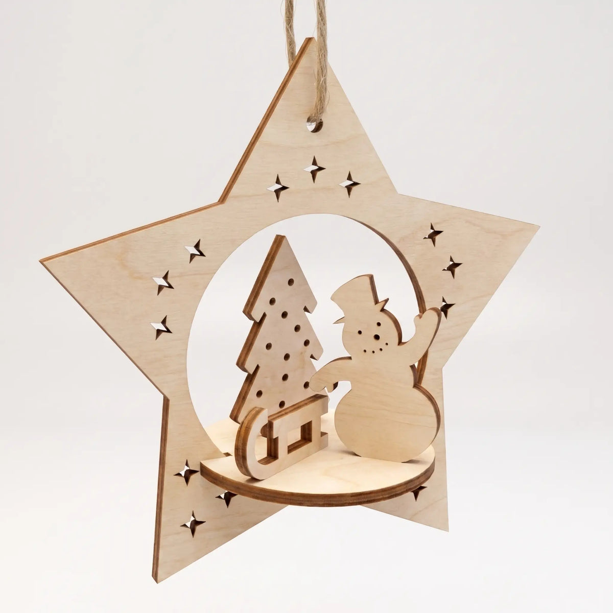 Laser cut plywood star bauble ornament with 3D diorama of cheerful snowman and holiday tree on sled.