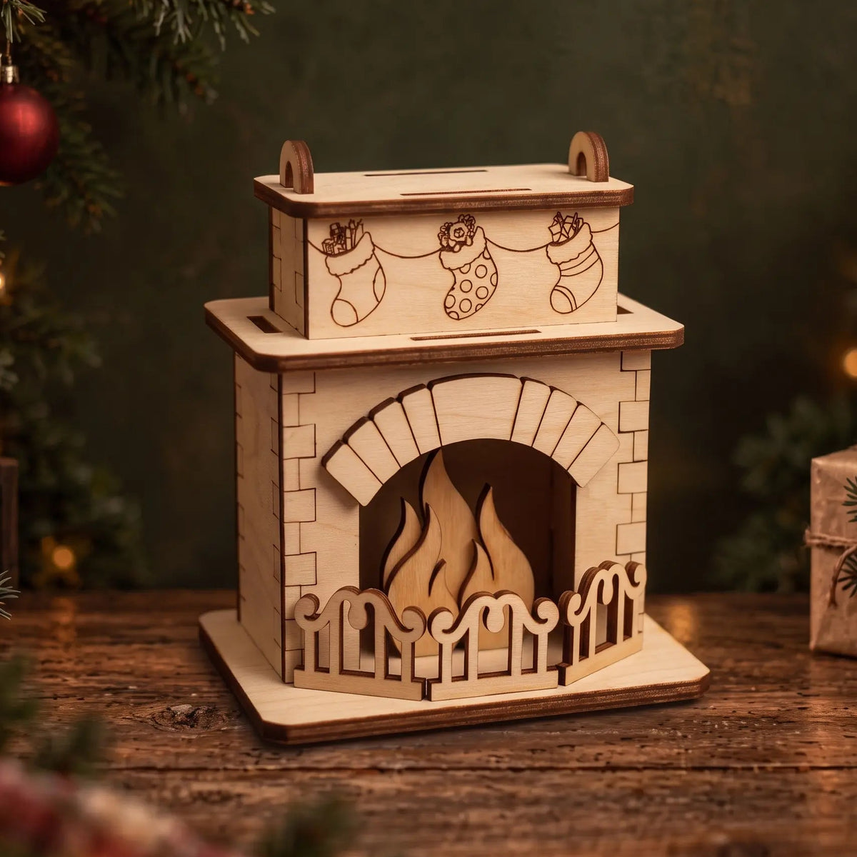 Laser cut plywood fireplace model with engraved stockings on mantel, placed on rustic wooden table by holiday tree