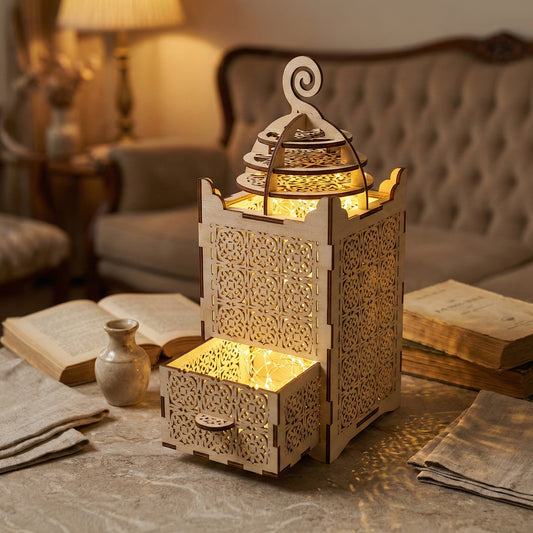 Elegant laser cut wooden lantern in light finish, showcasing ornate filigree panels, open compartment with fairy lights, displayed in a comfortable home interior setting.