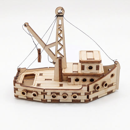 Side perspective view of laser cut plywood miniature fishing boat model with derrick crane tower on white background.