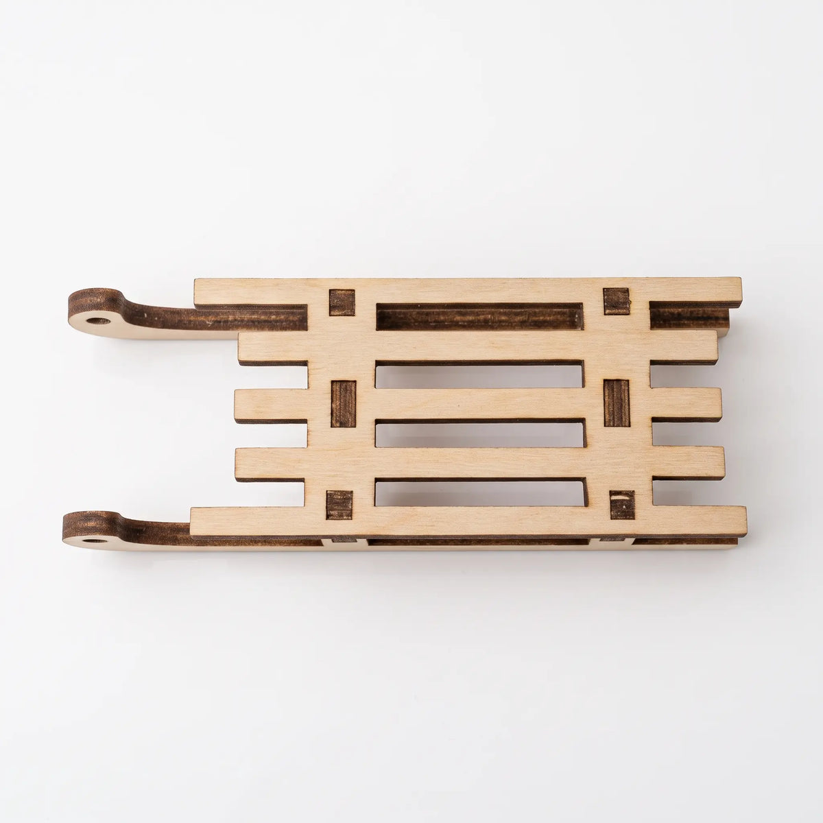Top flat lay view of a miniature wooden laser cut plywood sled ornament showing slatted seat on plain white.