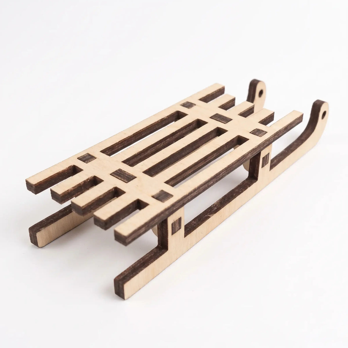 Rear angled perspective view of an unpainted laser cut plywood sled figurine set on white background.
