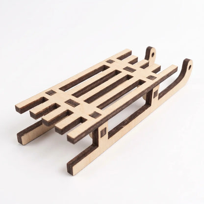 Rear angled perspective view of an unpainted laser cut plywood sled figurine set on white background.