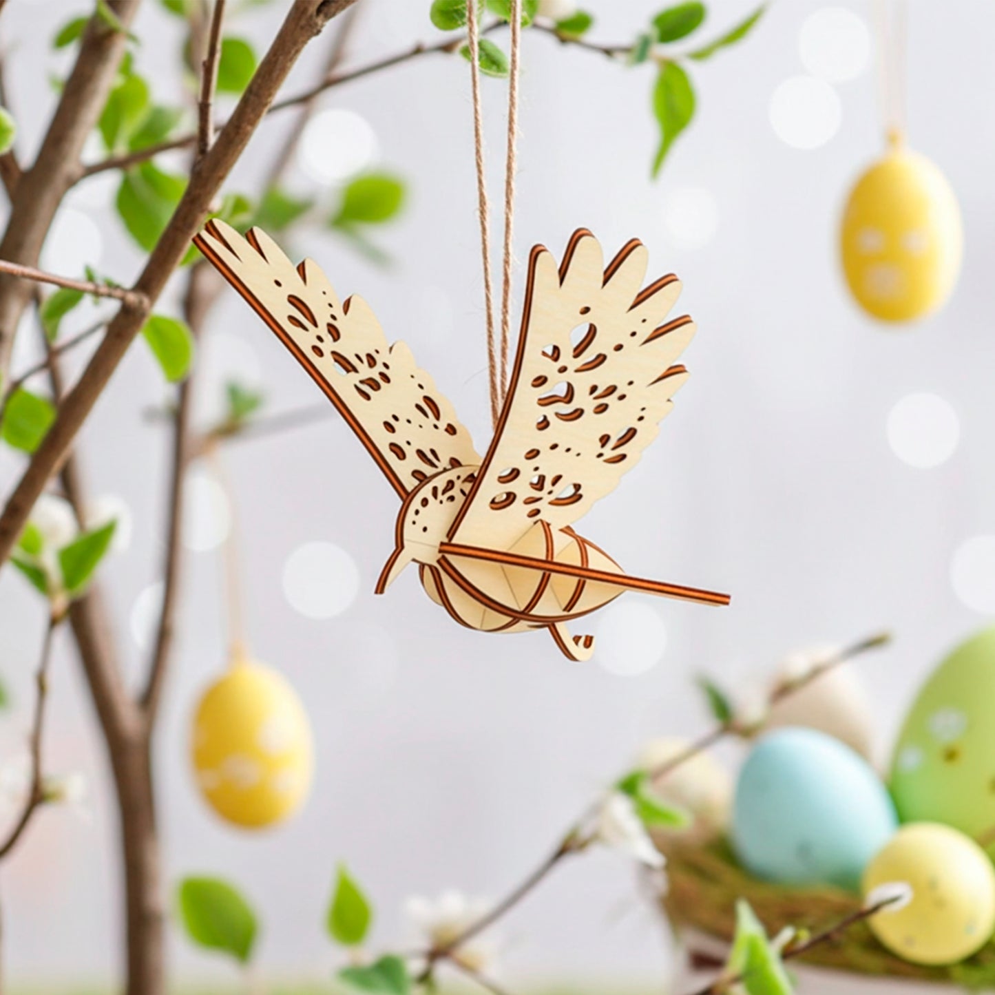  Laser-cut plywood wooden bird ornament hanging on a tree branch with soft spring leaves and pastel Easter eggs in the background