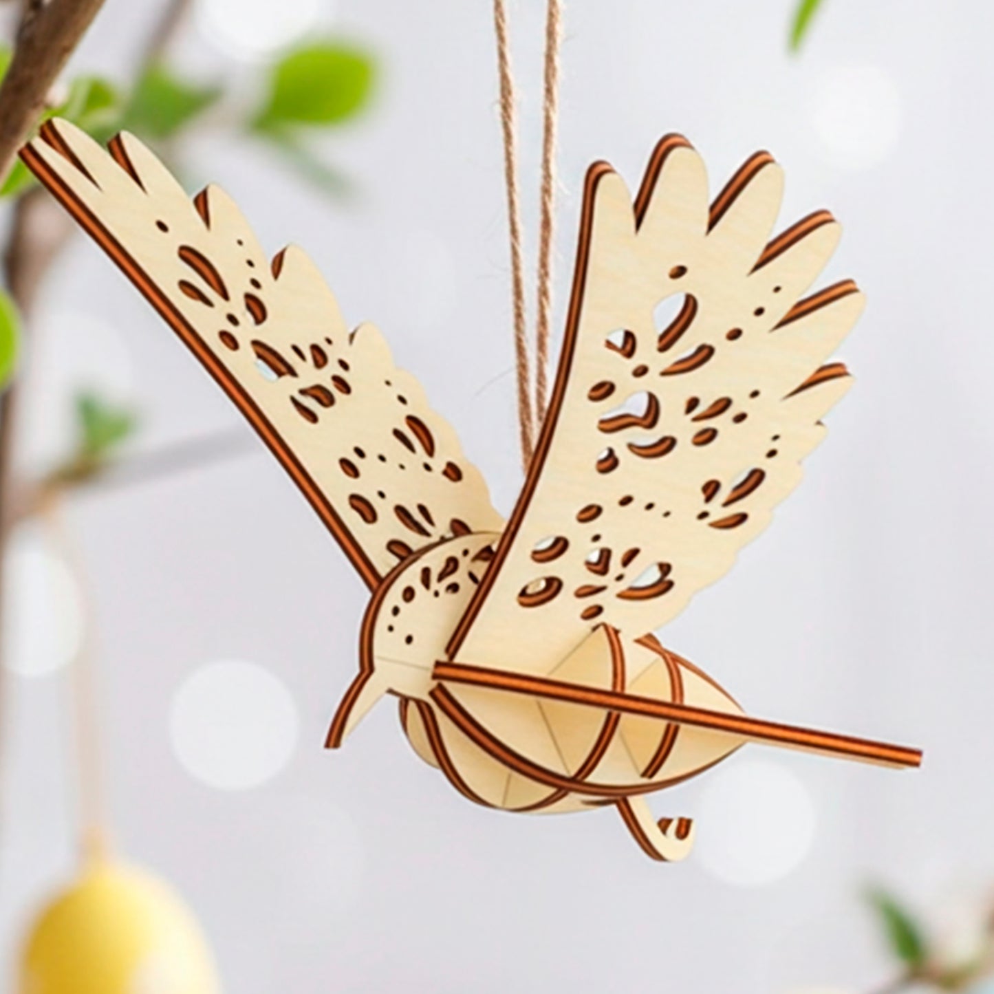  Laser-cut plywood wooden bird ornament hanging on a tree branch with soft spring leaves and pastel Easter eggs in the background