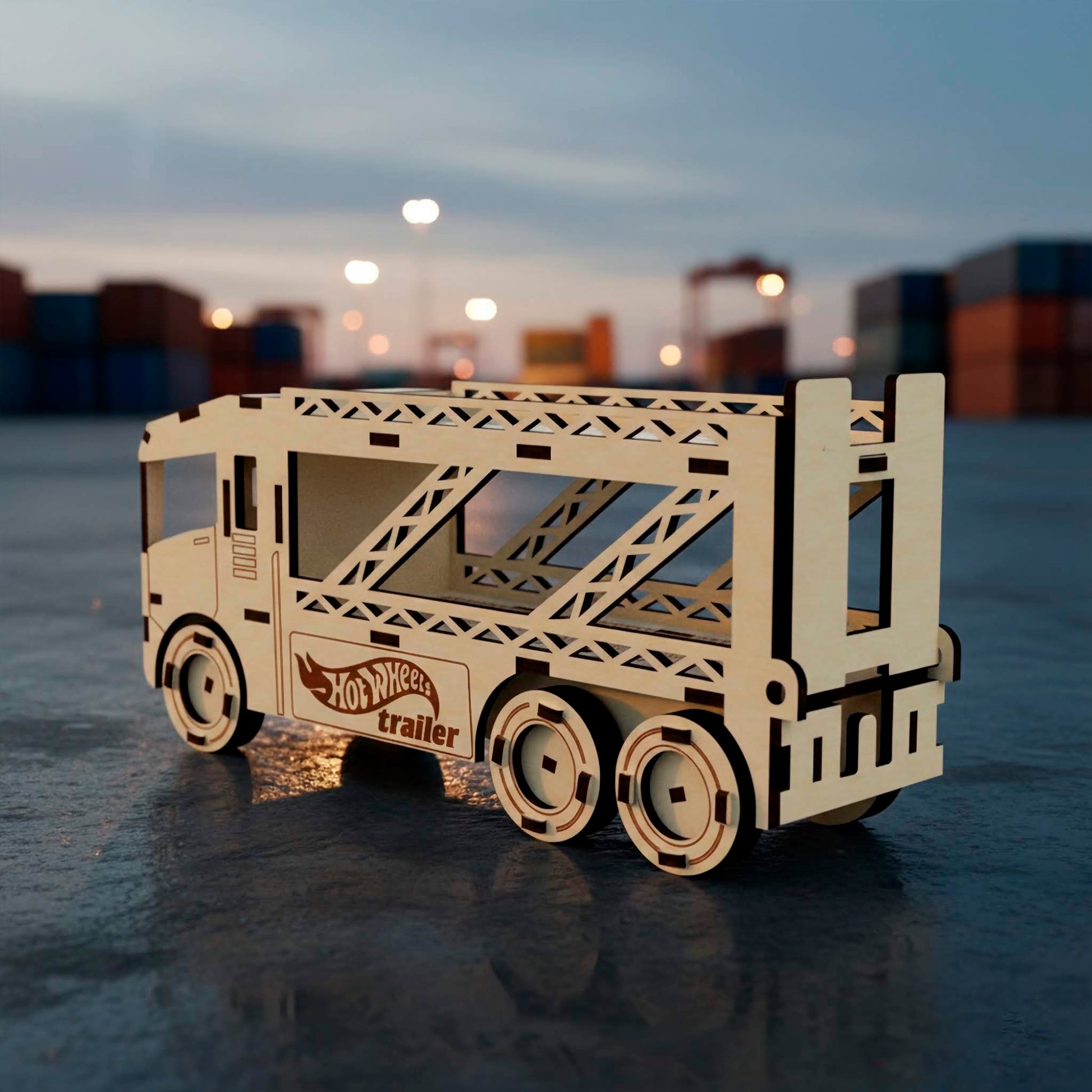 Rear three-quarter view of a laser cut wooden plywood car transport truck. Shows the structural plywood supports of the two-tier trailer and heavy-duty triple axles. The model is positioned on a wet asphalt surface at a shipping terminal