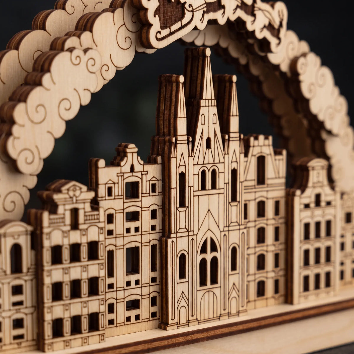 Close-up of laser cut plywood holiday city arch highlighting cathedral spire details, townhouse windows, and cloud border.