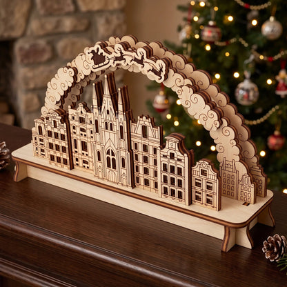 Natural laser cut plywood Christmas city arch diorama standing on wooden mantelpiece in front of illuminated holiday tree.