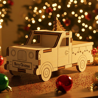 Laser cut wooden Small Christmas Truck ornament loaded with a tiny Christmas tree in the bed, displayed against a cozy blurred Christmas tree and fairy lights background.