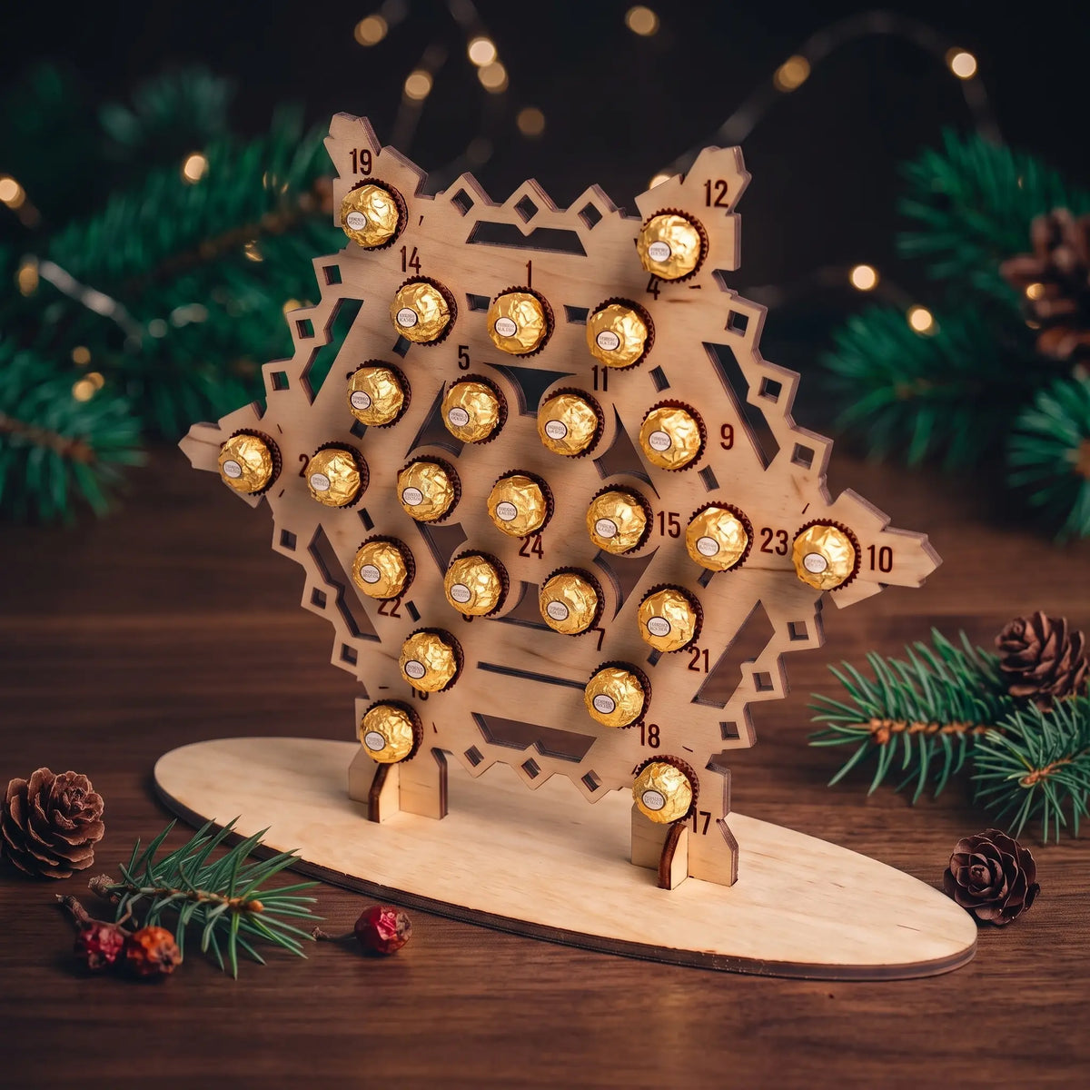 Angled view of laser cut plywood snowflake advent calendar filled with foil chocolates on a wooden holiday table.