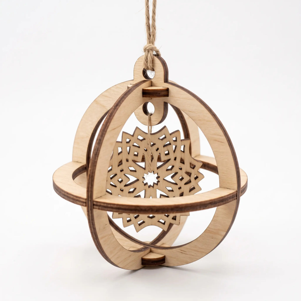 Front-angle view of 3D laser cut plywood sphere bauble with suspended layered snowflake motif on white.